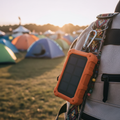 Solar power bank clipped to festival backpack in golden hour sunlight